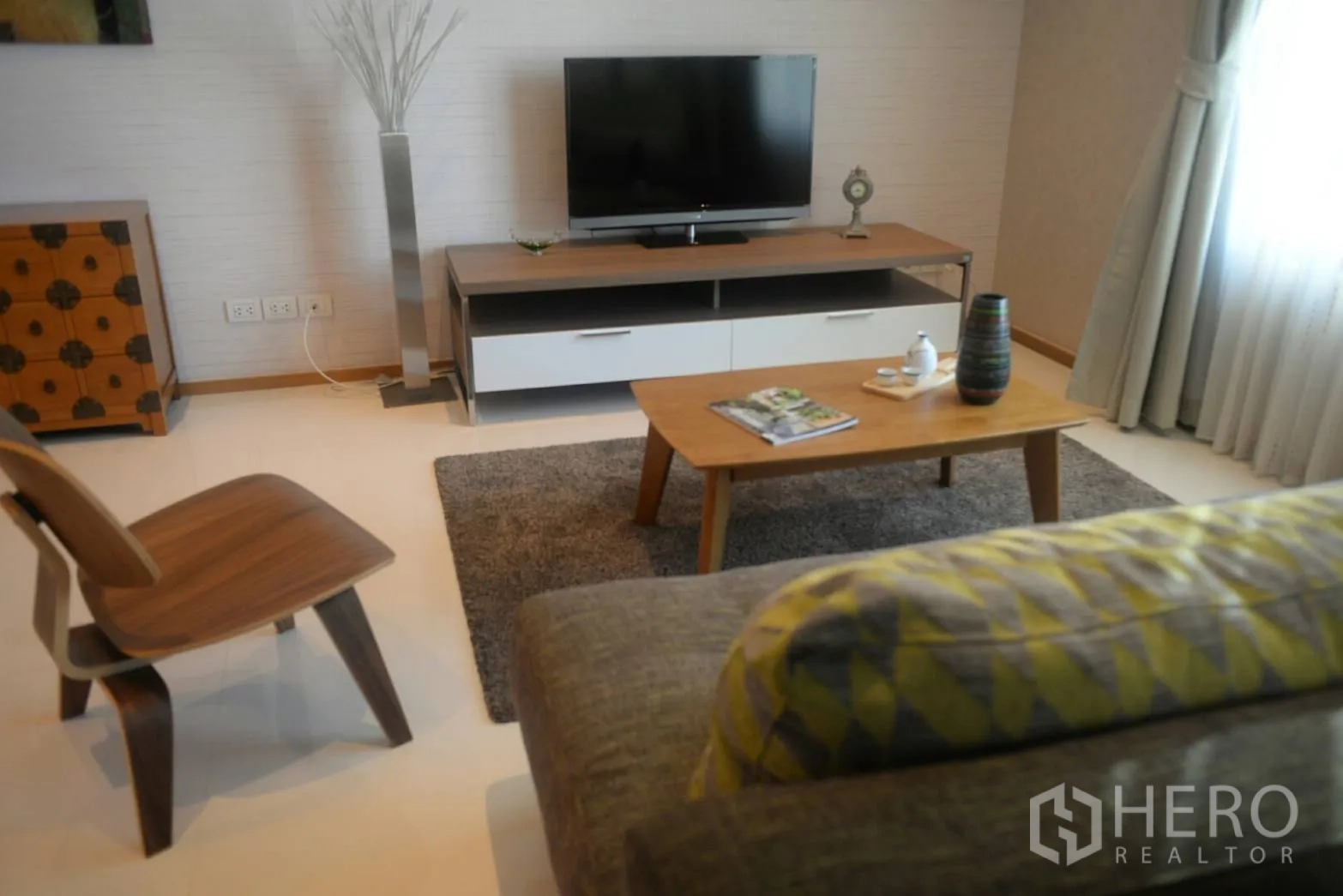 公寓 出租或出售在Khlong Toei, Bangkok - 舒适起居区，电视柜、茶几与地毯，旁有落地窗帘。