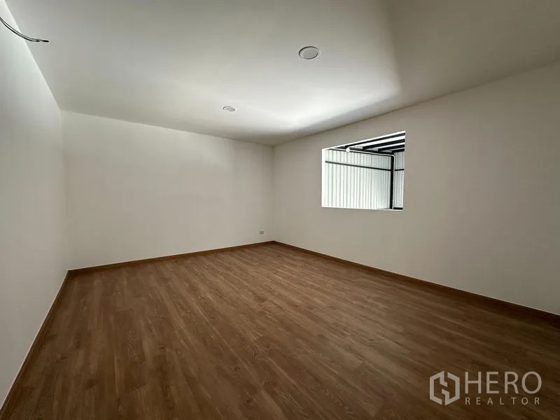Warehouse for rent - Bright office room inside a Suan Luang Bangkok warehouse with wood-look flooring, white walls and a window.