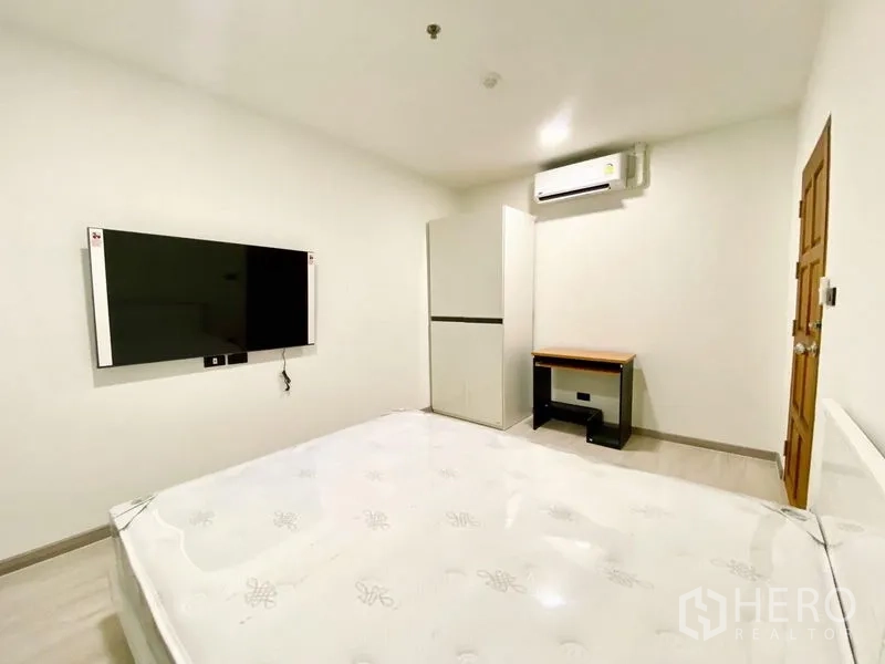 คอนโด ให้เช่า - ห้องนอนแขกมีทีวีติดผนัง ตู้เสื้อผ้า โต๊ะทำงาน และเครื่องปรับอากาศ