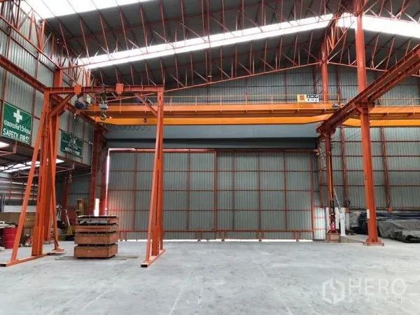 Warehouse for rent in Samut Prakan - Close view of a traveling overhead crane and gantry under a skylit roof inside the warehouse.