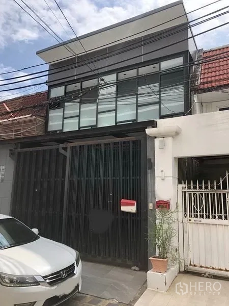 Home Office for rent in Khlong Toei, Bangkok - Modern two-storey home office exterior in Khlong Toei with full-width glass windows, tall sliding metal gate and a small driveway.