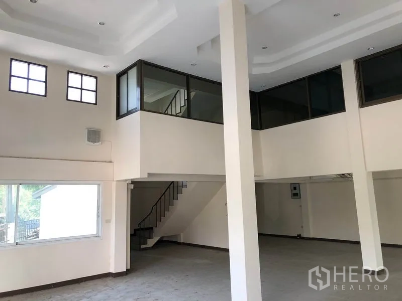 Shophouse for sale in Lam Luk Ka, Pathum Thani - Spacious hall with mezzanine offices, staircase, and recessed ceiling lights.