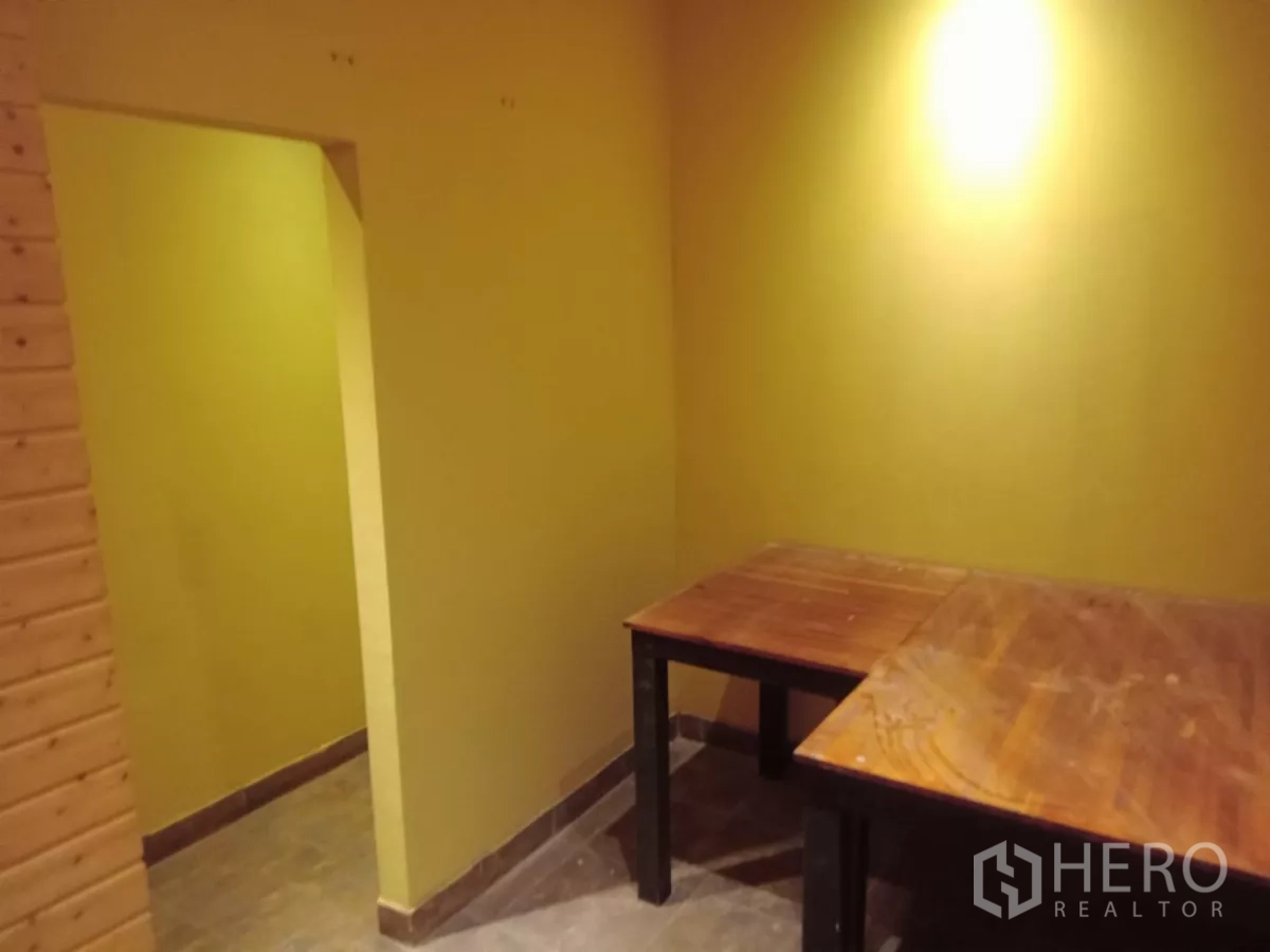 独立式住宅 出租在Phaya Thai, Bangkok - 黄色墙面的功能小房，摆放木桌，适合办公或备餐区。