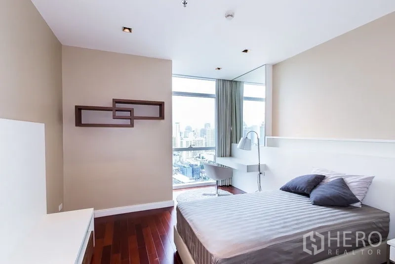 Condominium for rent in Pathum Wan, Bangkok - Bedroom with city view, wall art, and built-in floating desk.