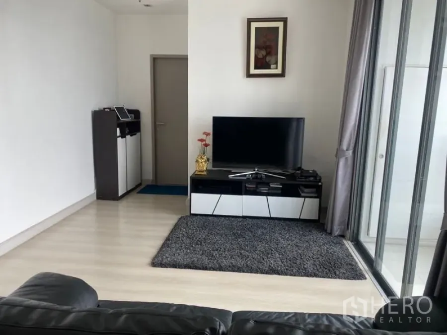 公寓 出售在Phra Khanong, Bangkok - 采光良好的客厅，电视柜与地毯，落地移门通往阳台