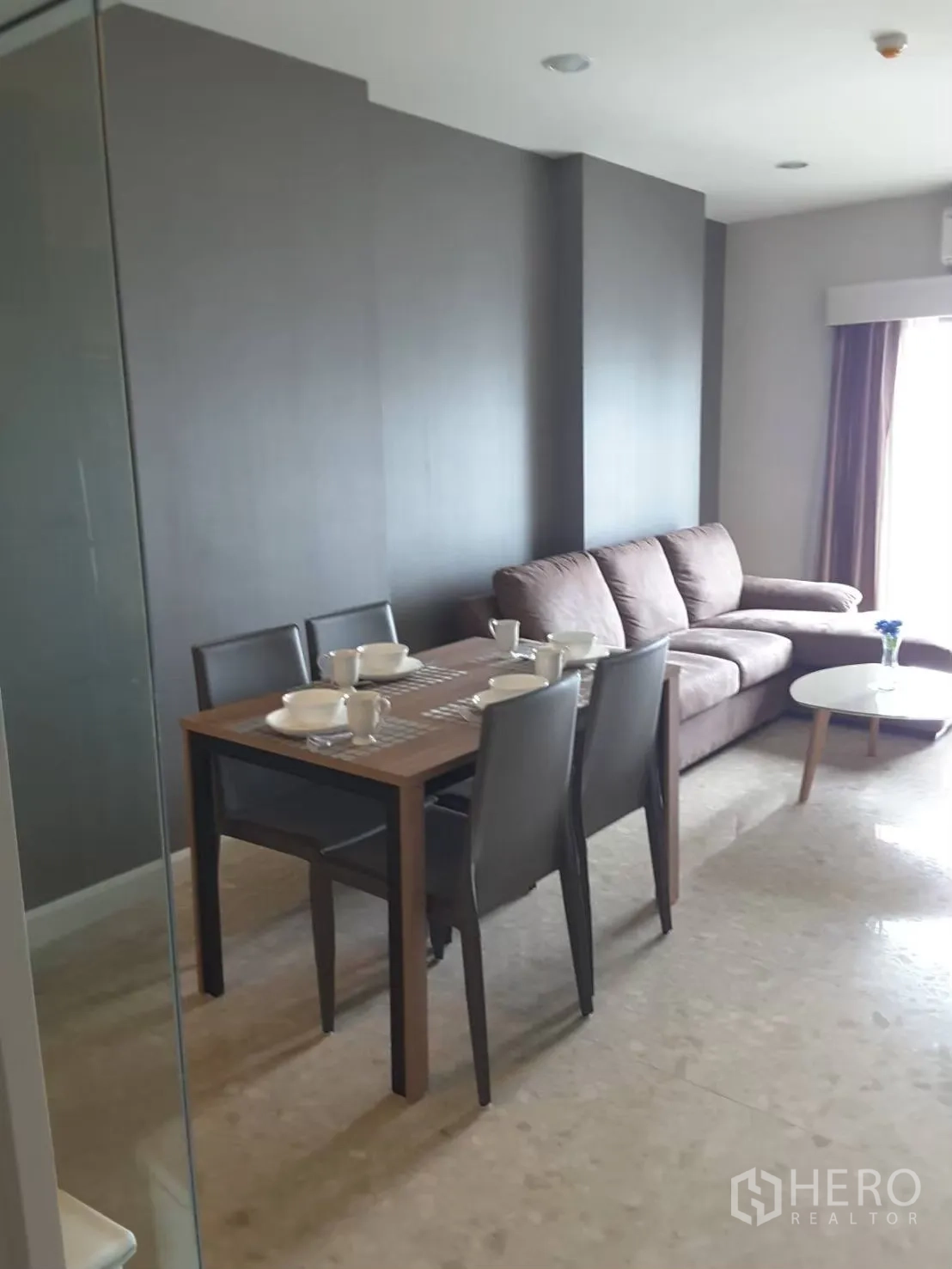 คอนโด ให้เช่าในKhlong Toei, Bangkok - โต๊ะอาหาร 4 ที่นั่ง ข้างผนังสีเทาและโซฟา