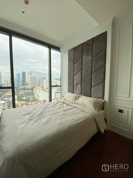 Condominium for rent in Watthana, Bangkok - Master bedroom with tall upholstered headboard and panoramic floor-to-ceiling windows.