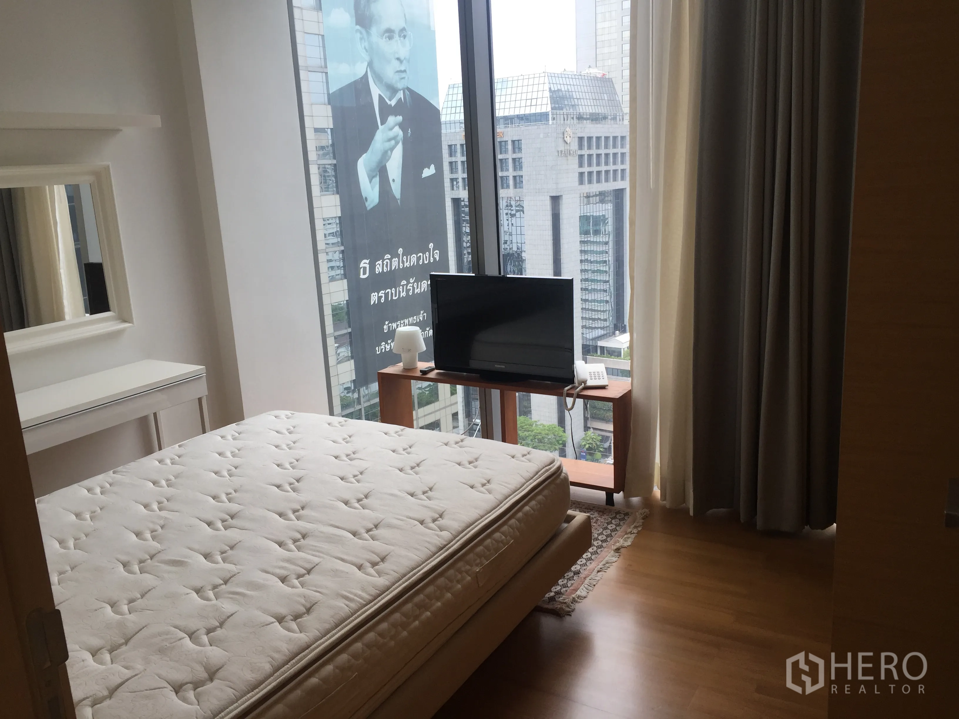 公寓 出租在Bang Rak, Bangkok - 卧室配大窗与天际线景观，木地板与小型电视柜。