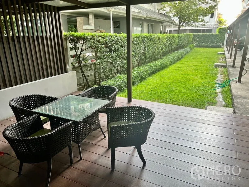 คอนโด ให้เช่าในBang Kho Laem, Bangkok - ระเบียงพักผ่อนแบบมีหลังคา ชุดโต๊ะหวาย มองเห็นสนามหญ้าและแนวรั้วต้นไม้