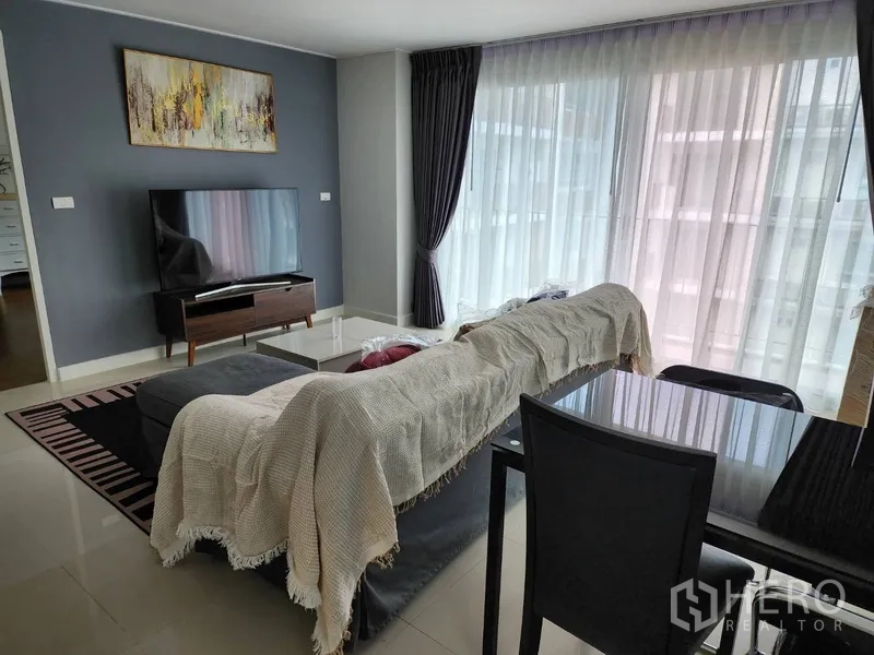 公寓 出租在Watthana, Bangkok - 客厅配电视柜、薄纱窗帘、深色主墙与四人餐桌。