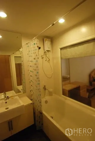 公寓 出租在Sathon, Bangkok - 浴室配浴缸、花洒、洗手台与镜柜，灯光温暖。