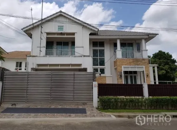 บ้าน ขายในLat Krabang, Bangkok - บ้านเดี่ยวสองชั้นย่านลาดกระบัง กรุงเทพฯ พร้อมประตูเหล็กบานเลื่อน ระเบียง หน้าต่างกระจกสูง และผนังอ磚ตกแต่ง บนลานปูพื้นหน้าบ้าน