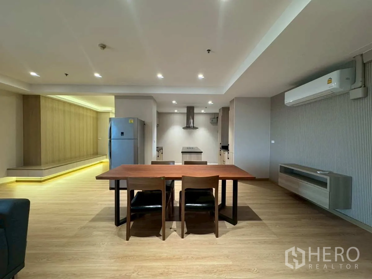 Condominium for rent or sale in Khlong Toei, Bangkok - Dining zone with wooden table, LED-lit feature wall and modern kitchen.