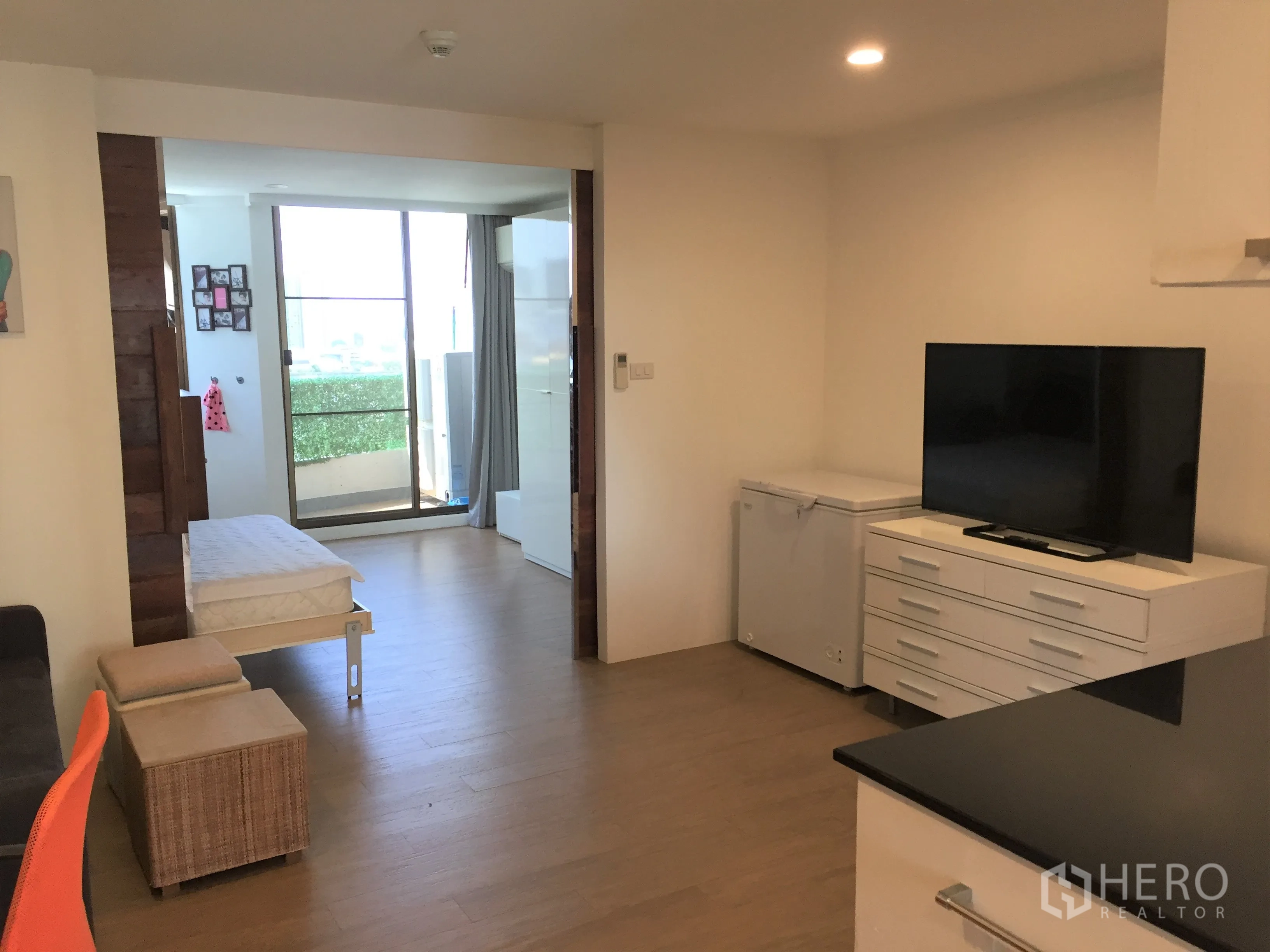 公寓 出租在Watthana, Bangkok - 起居区配电视柜与座位，玻璃门通向阳台。