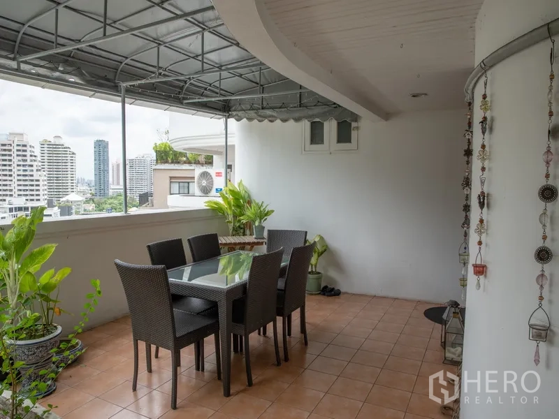 Apartment for rent in Khlong Toei, Bangkok - Covered outdoor dining area with table set and skyline outlook.