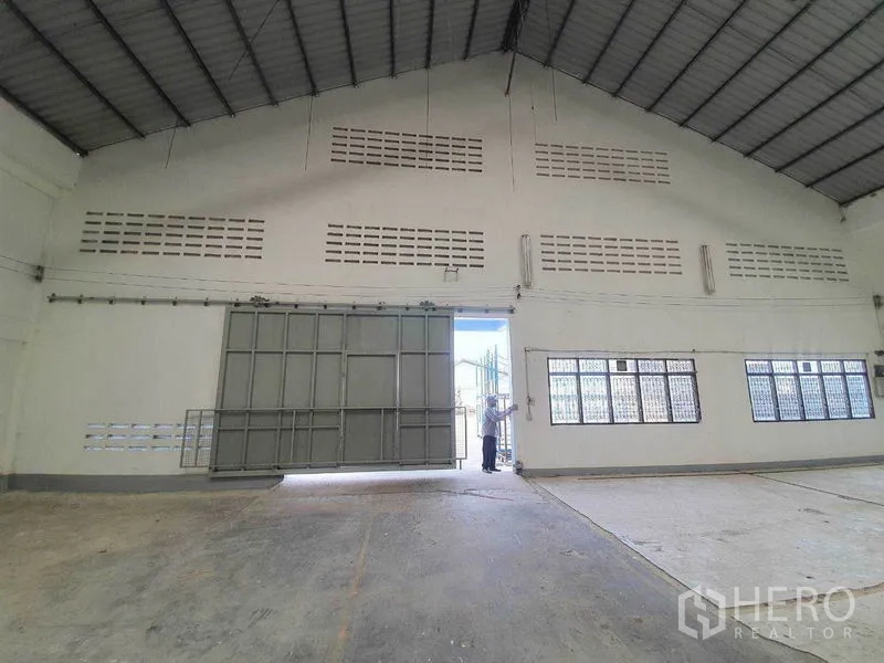 货栈 出租在Nakhon Pathom - 室内朝向大型推拉金属门，山墙通风砖带。