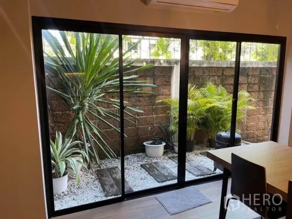 ทาวน์เฮาส์ ขายในBang Phli, Samut Prakan - สวนหย่อมส่วนตัวพร้อมกระถางต้นไม้และทางเดินกรวด มองผ่านประตูกระจกบานเลื่อน.