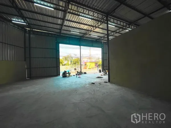 Warehouse for rent in Sai Mai, Bangkok - Spacious high-ceiling warehouse interior with concrete floor and a wide opening to the front yard.