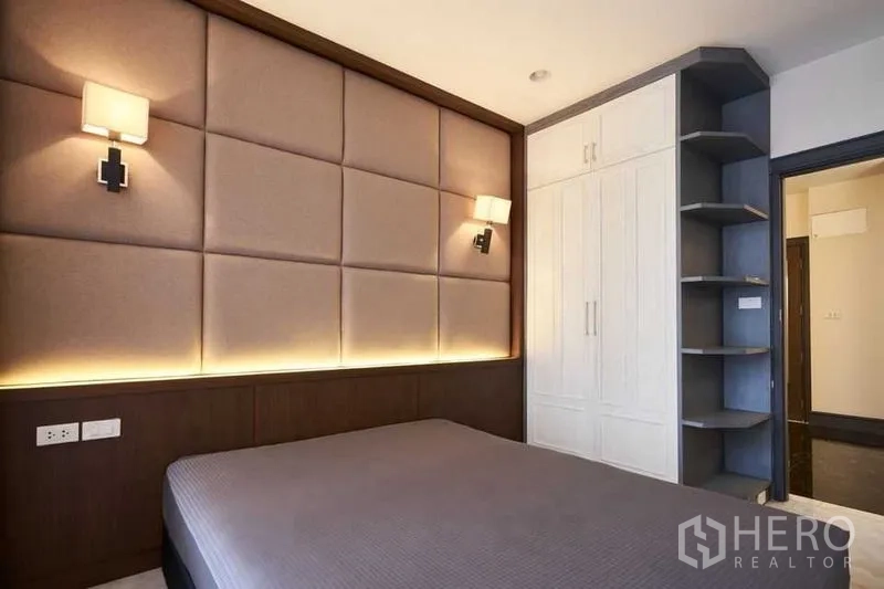 Condominium for sale in Ratchathewi, Bangkok - Bedroom with padded headboard, integrated lighting and built-in wardrobe with corner shelves.