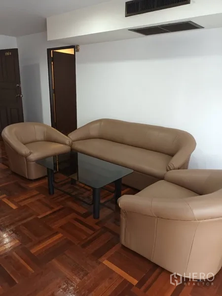 คอนโด ให้เช่าในDin Daeng, Bangkok - มุมนั่งเล่นโซฟาหนัง 3 ชิ้นรอบโต๊ะกลางกระจกสีดำ บนพื้นไม้ปาร์เกต์