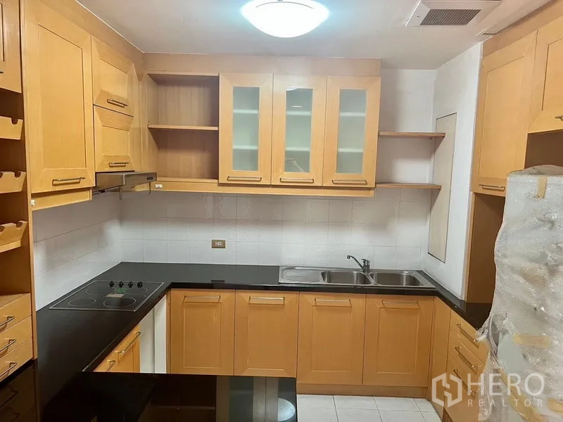 คอนโด ให้เช่าในBang Kho Laem, Bangkok - ครัวรูปตัวยู ตู้ไม้โทนอ่อน ท็อปสีดำ เตาไฟฟ้า และอ่างล้างจานคู่