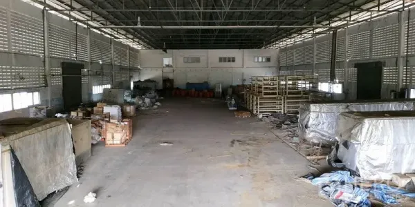 Factory for rent in Chachoengsao - Open warehouse hall with ventilated block walls, storage racks, and a concrete floor.