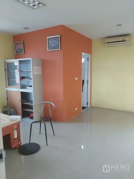 Warehouse for rent in Krathum Baen, Samut Sakhon - Office corner inside the warehouse with orange accent wall, cabinet and air conditioner.