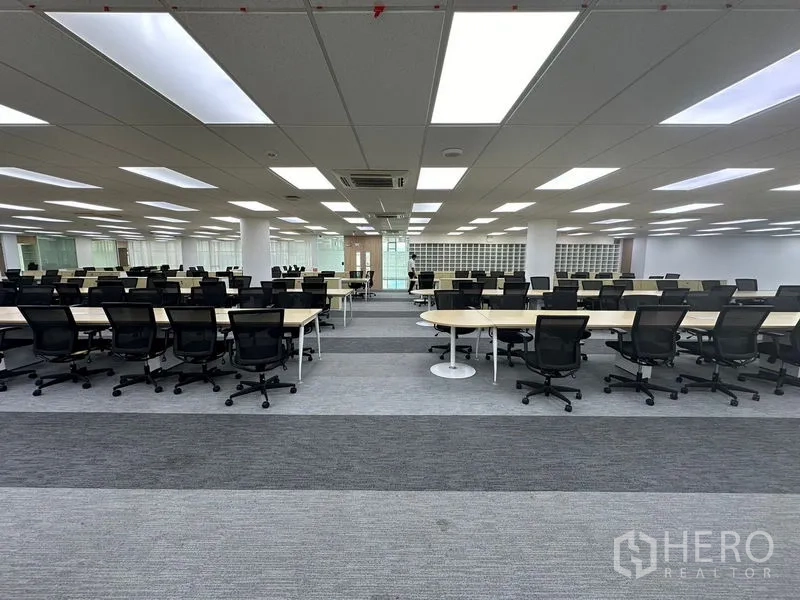Office Space for rent - Symmetrical open office featuring bench desks and abundant overhead lighting.