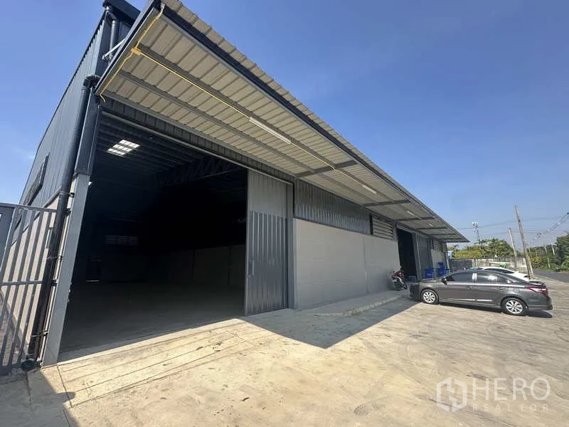 Warehouse for rent in Bang Bua Thong, Nonthaburi - Modern steel-frame warehouse exterior with wide sliding door, covered loading bay and parking area.