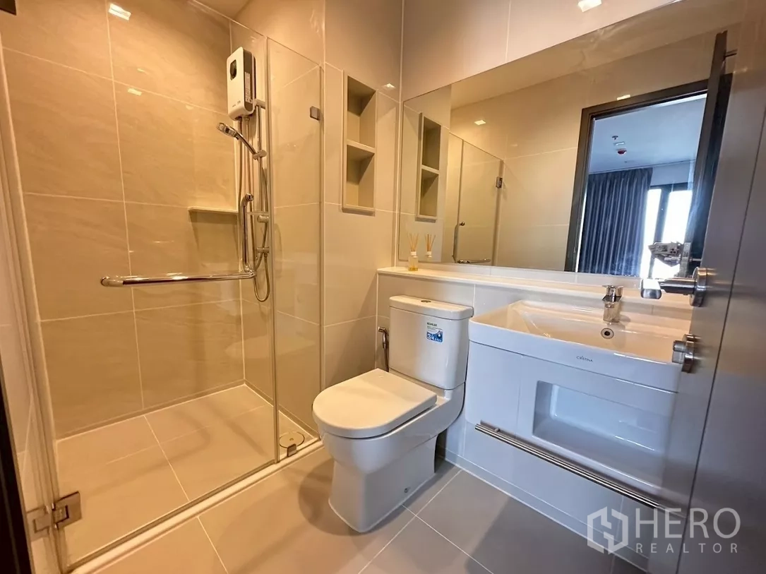 Condominium for rent in Chatuchak, Bangkok - Bright tiled bathroom with walk-in shower and wide mirror.
