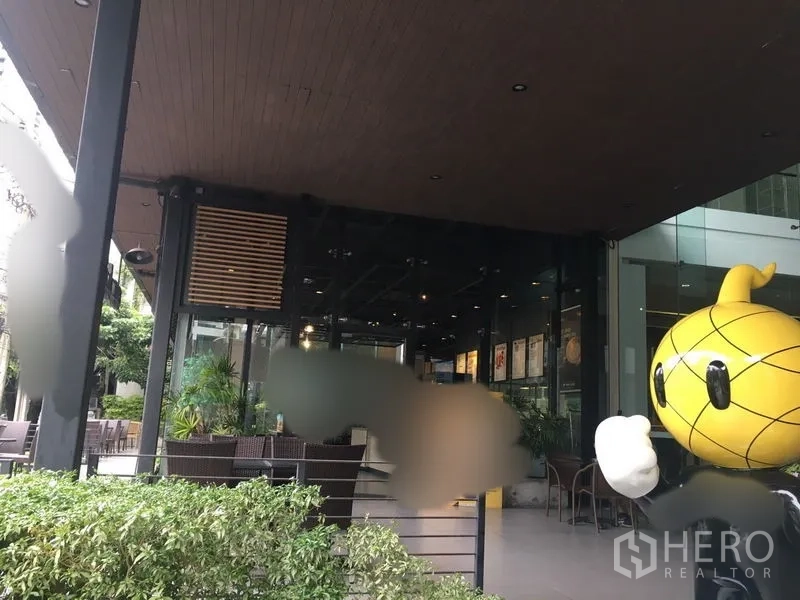 零售空间 出租在Khlong Toei, Bangkok - 带木质天花的半露天入口，玻璃店面与盆栽绿化及户外座椅。