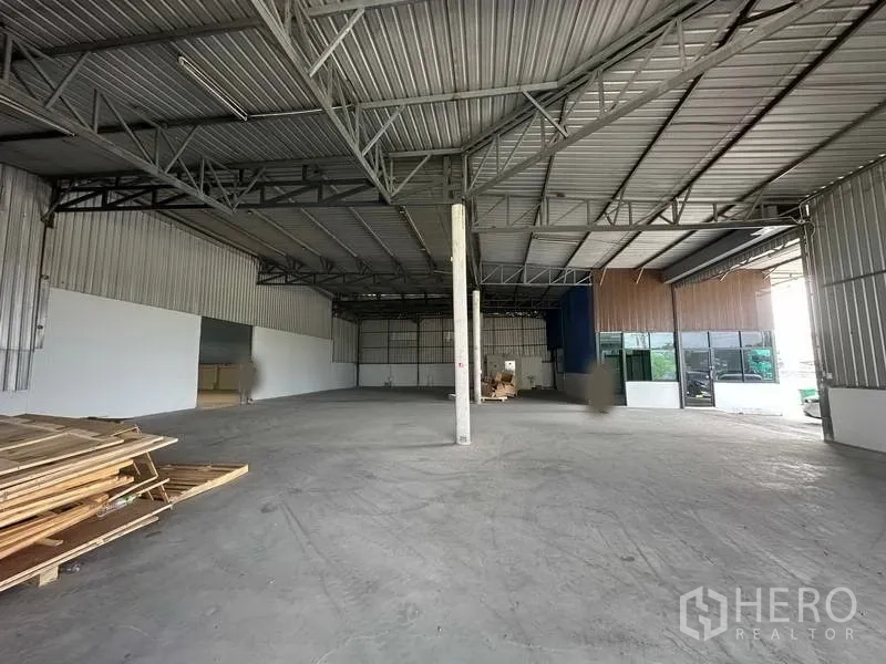 货栈 出租在Khlong Luang, Pathum Thani - 宽敞仓库内景，高钢结构屋顶，旁接玻璃立面的办公室。