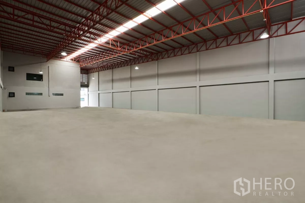 โรงงาน ให้เช่าในMueang Samut Sakhon, Samut Sakhon - มุมเอียงของโกดังพื้นสะอาด ไฟแขวนอุตสาหกรรมและโครงทรัสสีแดง.