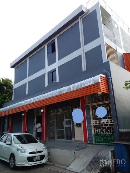 Retail Space for sale in Lam Luk Ka, Pathum Thani - Three-storey retail building with grey facade, orange accents and wide glass shopfront.