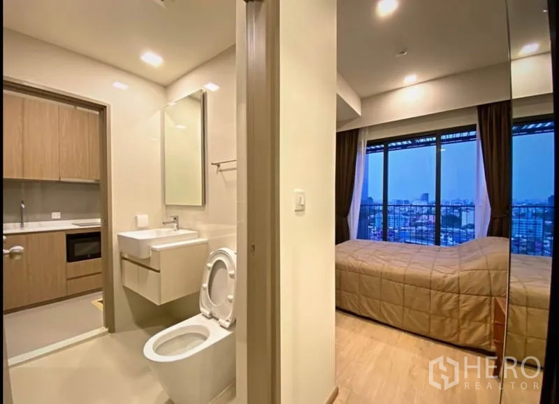 Condominium for sale in Chatuchak, Bangkok - Bathroom and bedroom layout with city-view window and mirrored wardrobe.