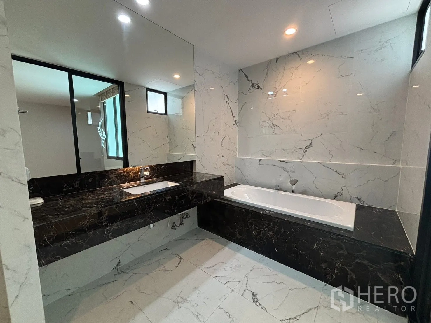 Townhouse for rent in Saphan Sung, Bangkok - Luxurious bathroom with a long black marble vanity and a built-in bathtub.