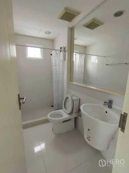 联排别墅 出租在Wang Thonglang, Bangkok - 明亮浴室，设淋浴区、坐便器、大镜面与台盆。