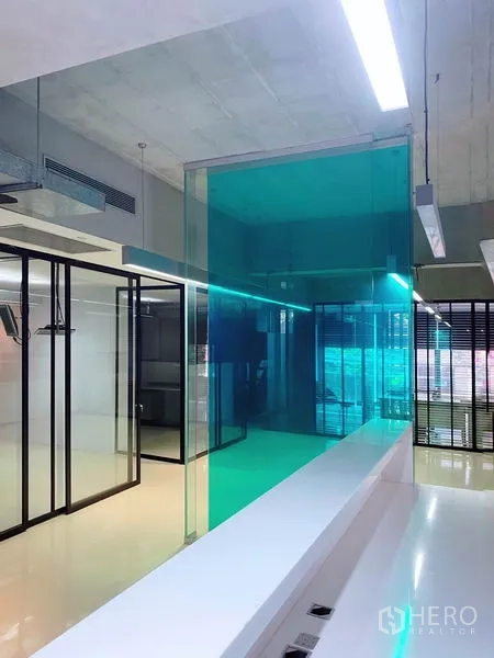 สำนักงาน ให้เช่าในPhaya Thai, Bangkok - ภายในออฟฟิศสมัยใหม่ ผนังกระจกสีฟ้าเขียว ห้องประชุม กรอบกระจกสีดำ พื้นเงา และเพดานลอฟท์ ในพญาไท