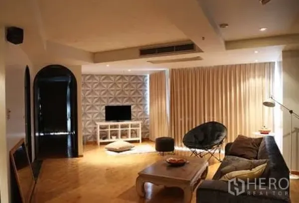 Condominium for rent in Ratchathewi, Bangkok - Spacious living room with sofa, TV console, floor lamp, curtains and recessed lighting.