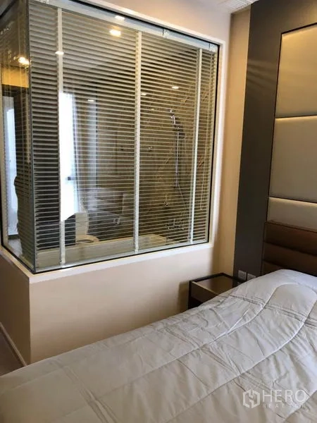คอนโด ให้เช่าในWatthana, Bangkok - ห้องนอนพร้อมหัวเตียงบุผ้า และหน้าต่างกระจกมองเข้าห้องน้ำ มีมู่ลี่บังสายตา
