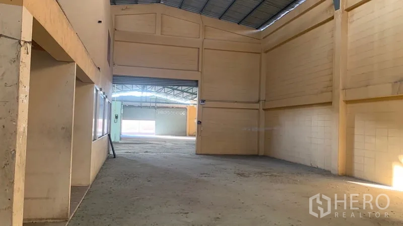 Warehouse for rent in Mueang Nakhon Pathom, Nakhon Pathom - Wide central aisle of the warehouse showing tall walls and roof trusses toward the entrance.