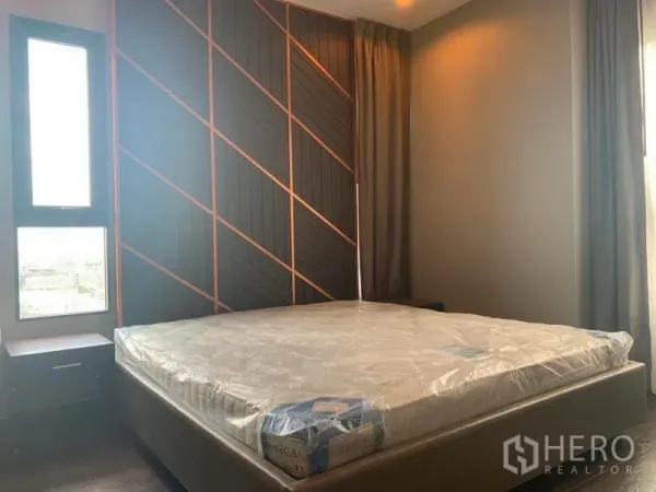 Condominium for rent in Watthana, Bangkok - Master bedroom with geometric accent wall, king bed and tall curtained windows.