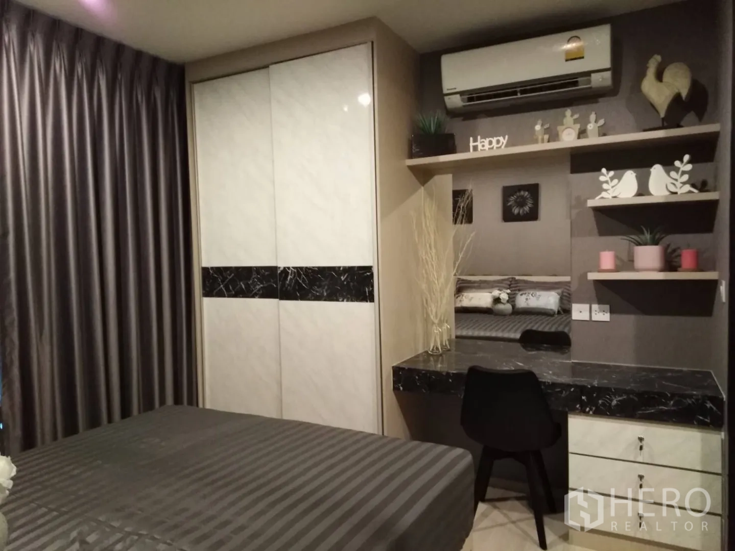 Condominium for rent in Huai Khwang, Bangkok - Bedroom with striped bedding, built-in wardrobe and marble-top work desk