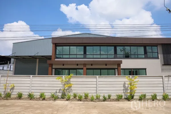 Factory for rent or sale in Bang Len, Nakhon Pathom - Street elevation of the factory and two-level office behind a secure perimeter wall with fresh landscaping.