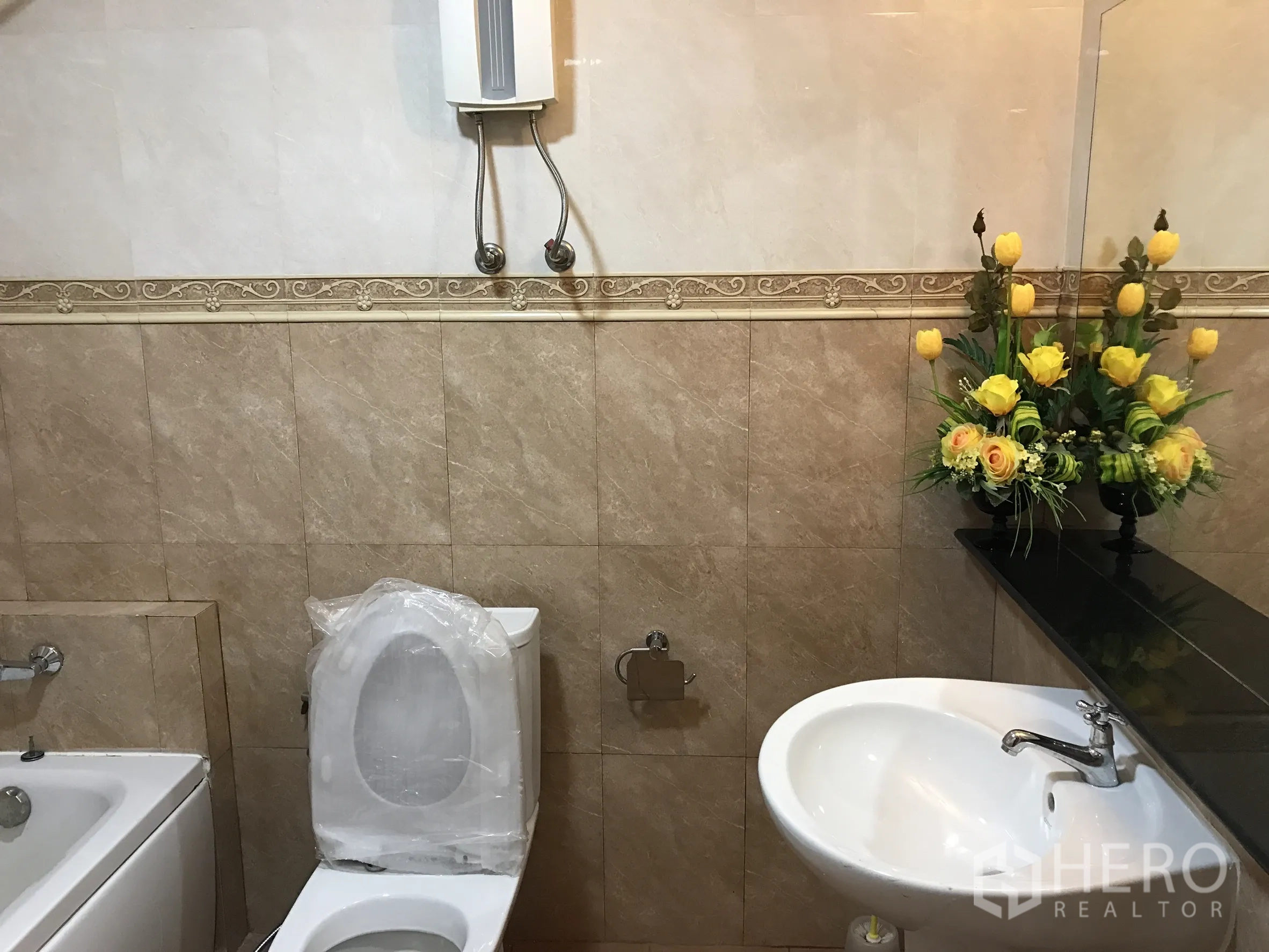 公寓 出租在Khlong Toei, Bangkok - 瓷砖浴室，配浴缸、马桶、洗手盆和黄色花饰。