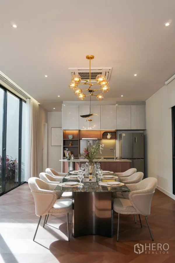 独立式住宅 出租或出售在Bang Kapi, Bangkok - 餐厅在雕塑感金色吊灯下，对面为时尚一体化厨房。