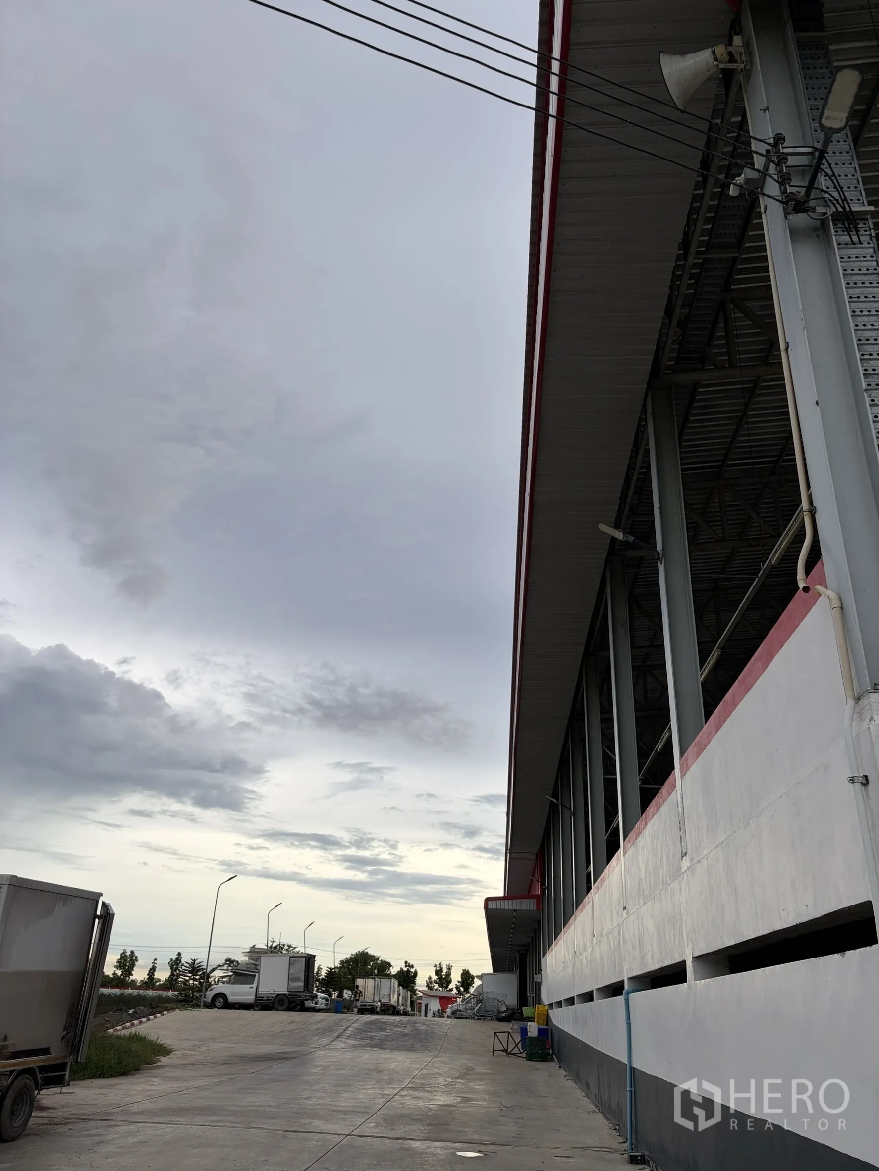 Factory for sale in Mueang Nakhon Pathom, Nakhon Pathom - Loading ramp and platform along factory facade with several trucks.