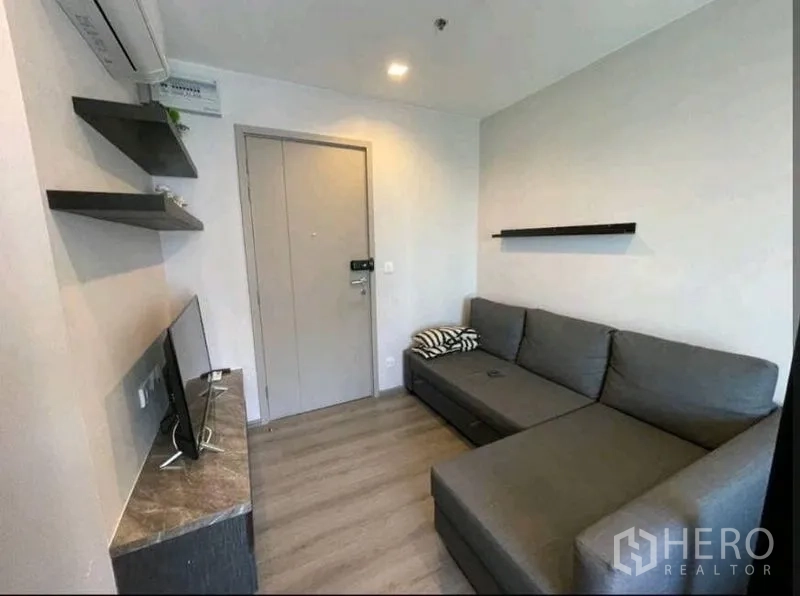 คอนโด ให้เช่าในYan Nawa, Bangkok - มุมนั่งเล่นอบอุ่น โซฟาแอลสีเทา ชั้นวางผนัง และชั้นวางทีวี