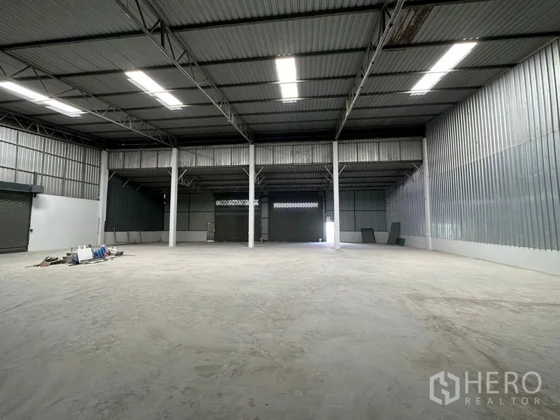 货栈 出租在Khlong Luang, Pathum Thani - 宽敞仓库大厅，设多扇卷闸门、挑高屋顶与采光天窗。