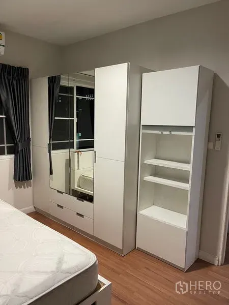 Detached House for rent in Bang Kapi, Bangkok - Bedroom featuring a white built-in wardrobe with mirrored doors, wood floors and dark drapes.